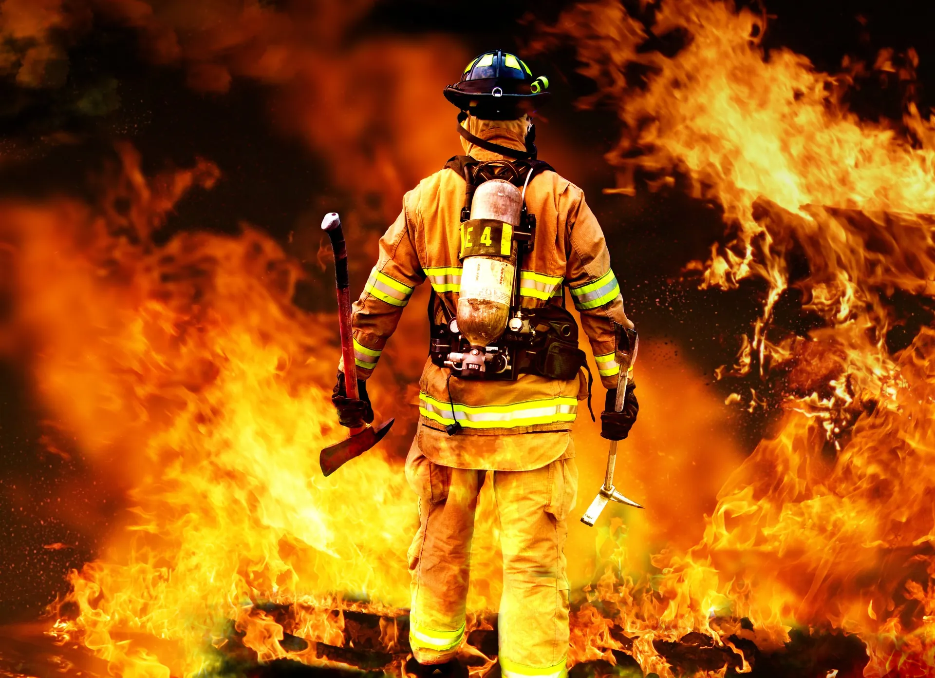 Firefighter in protective gear facing a large fire