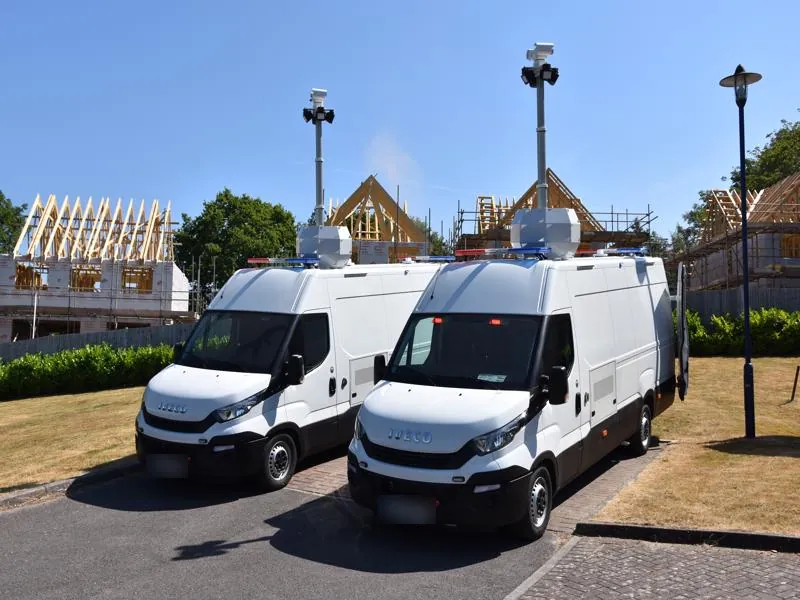 Two mobile surveillance vans with telescopic camera masts raised