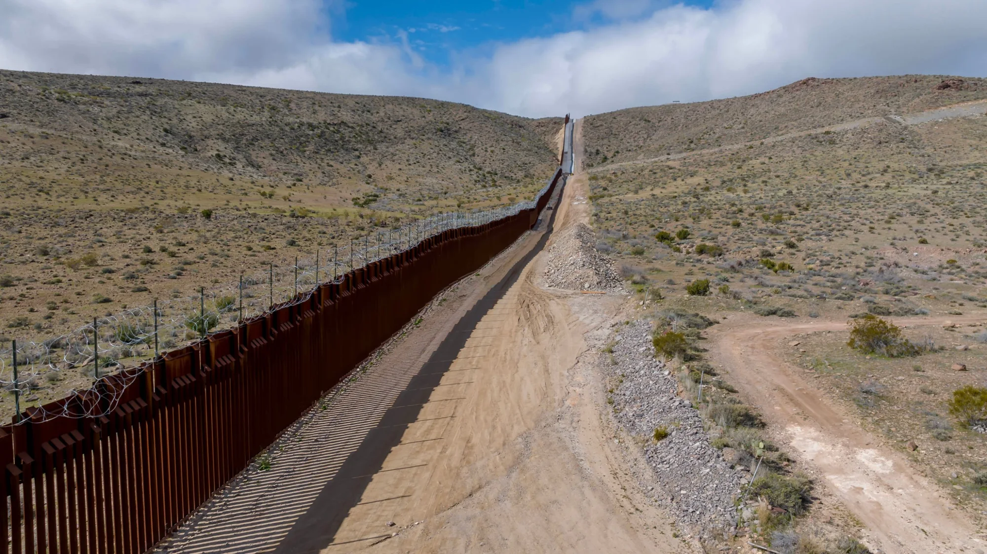 Border wall running across desert hills