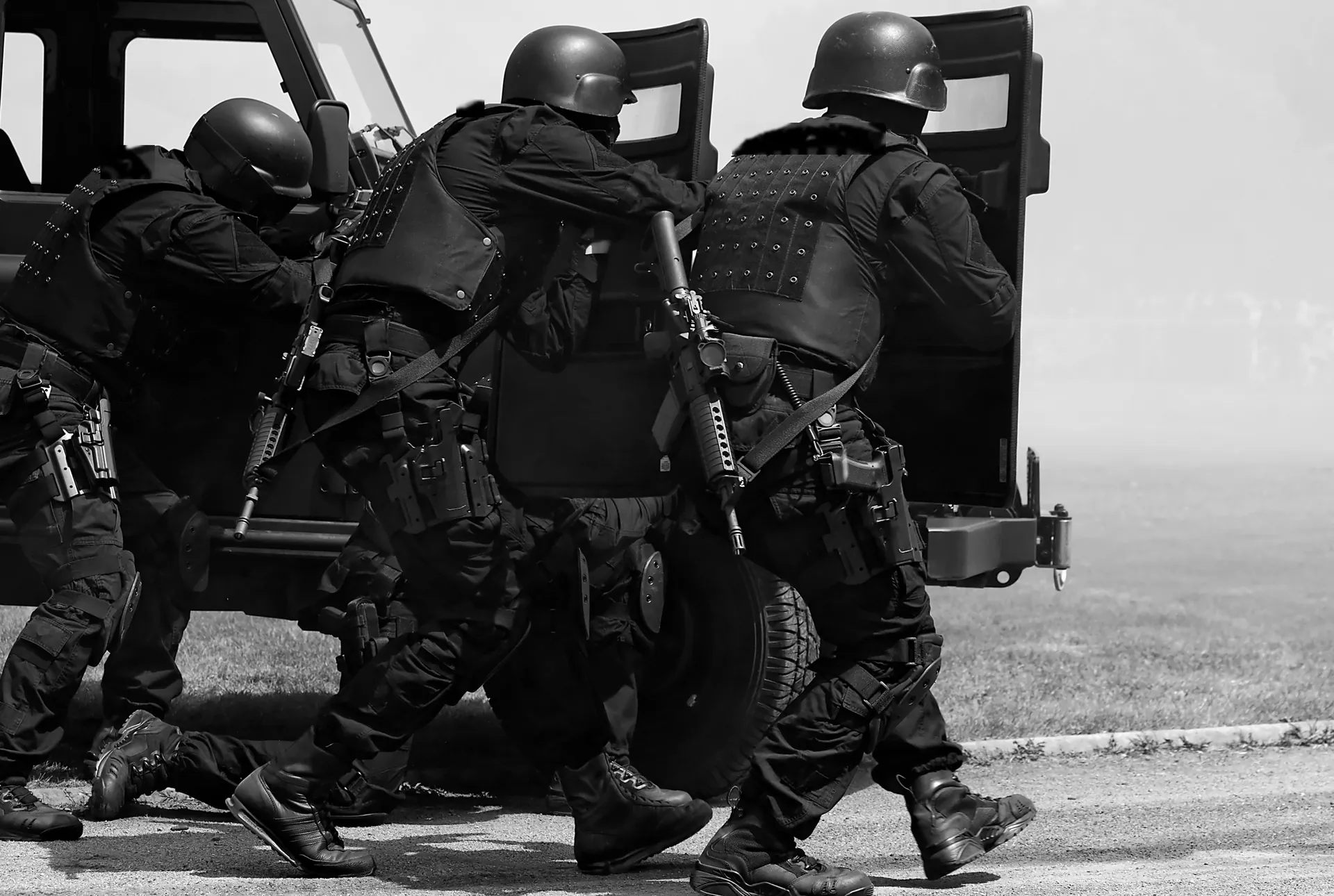Tactical police team advancing behind an armoured vehicle